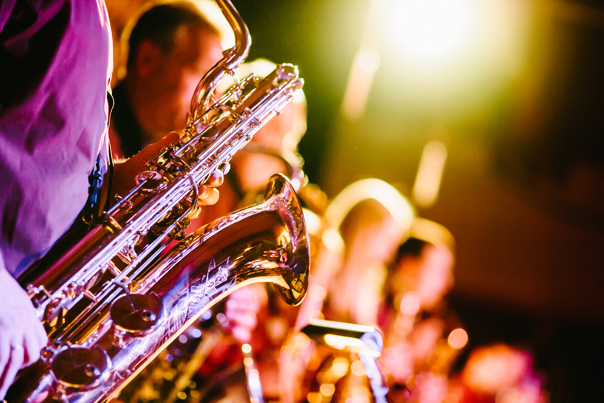 A saxophonist performing under warm stage lighting.