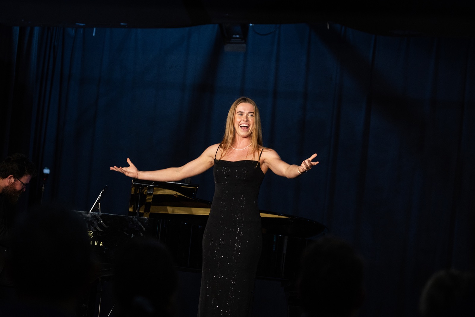 A soprano takes her bow beside a grand piano during a Festival Session.