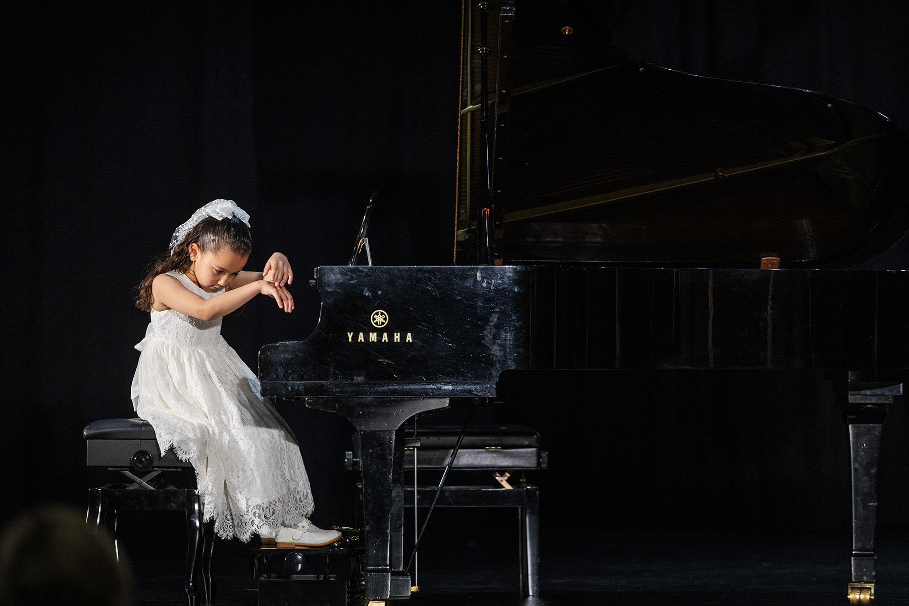 A pianist accompanies a young singer performing centre stage.