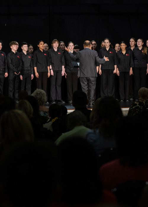 A school choir performs under their conductor's direction.