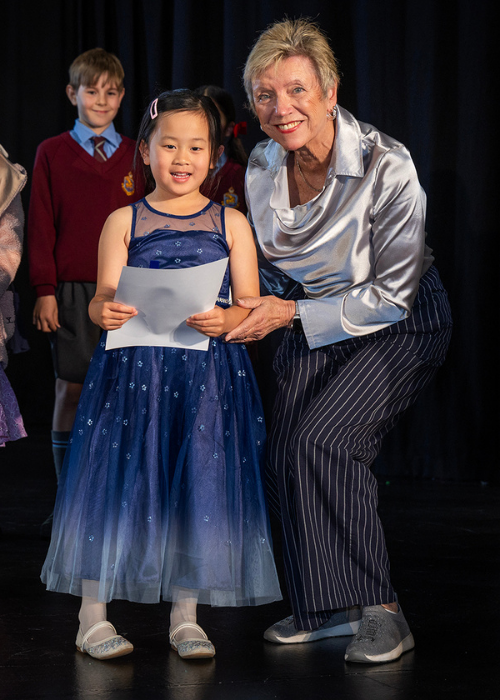 A young winner receives her certificate from a presenter.