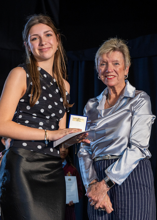 A senior winner receives her medallion from a presenter.